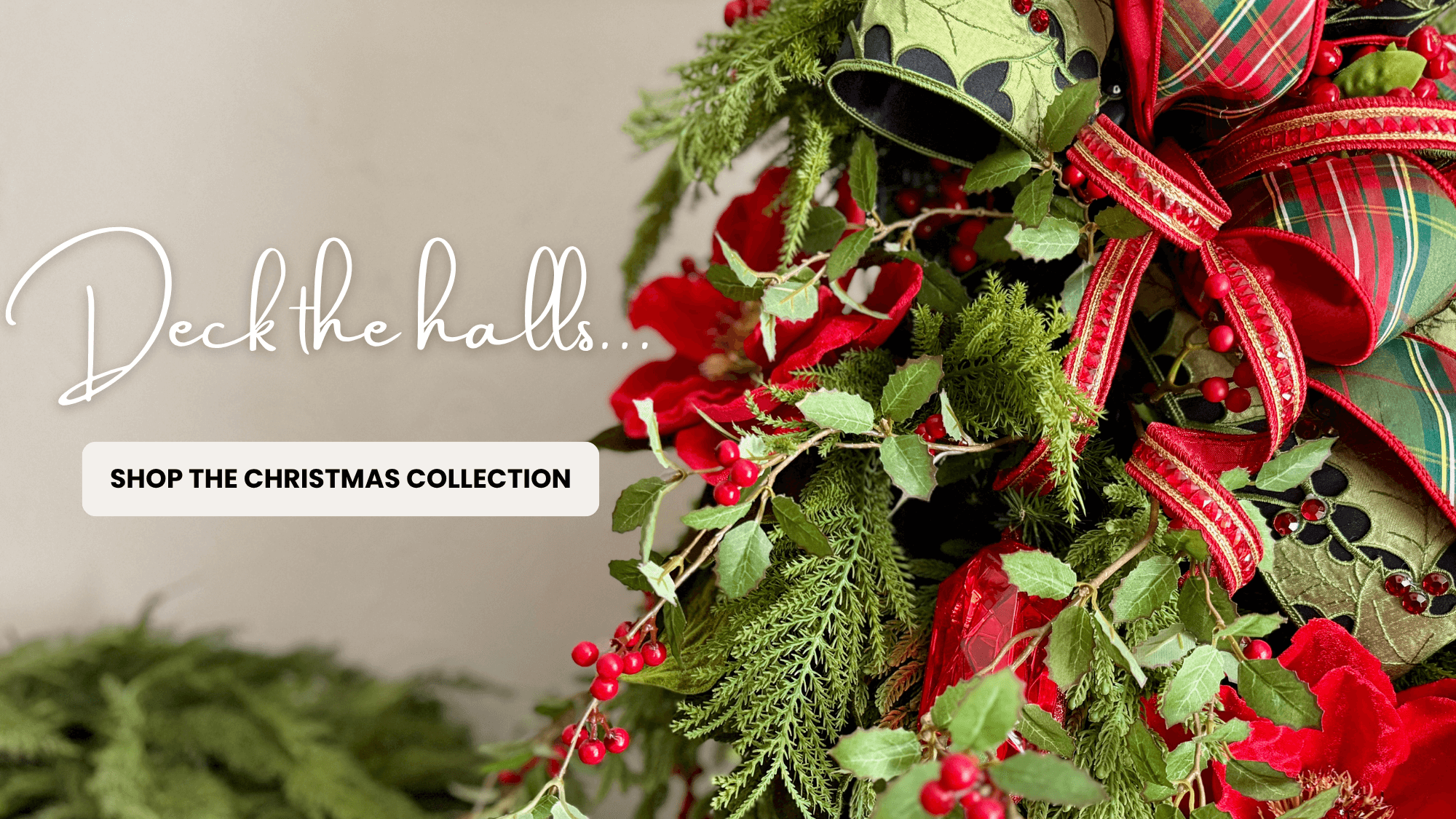 Decorative Christmas wreath with red and green ribbons and berries, with text 'Deck the halls promoting the Christmas Collection