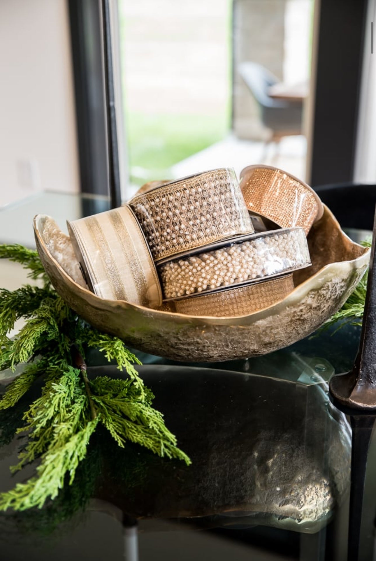 Wooden bowl with decorative ribbon on a table with greenery